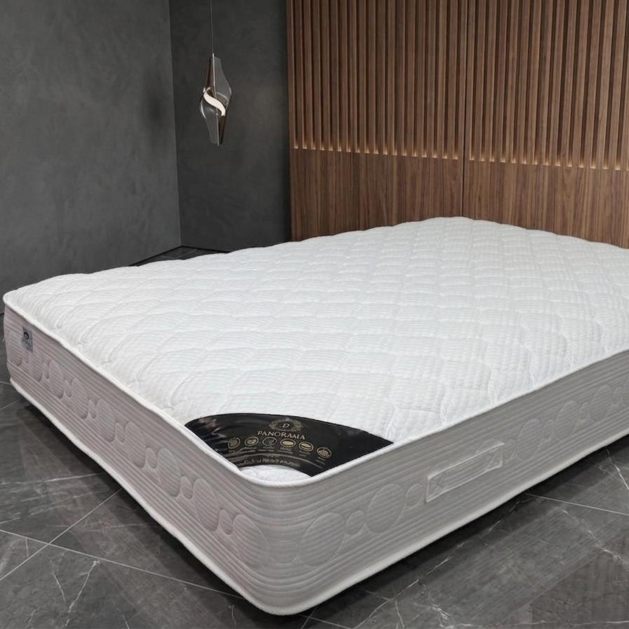 Mattress on a gray floor with wooden paneling in the background