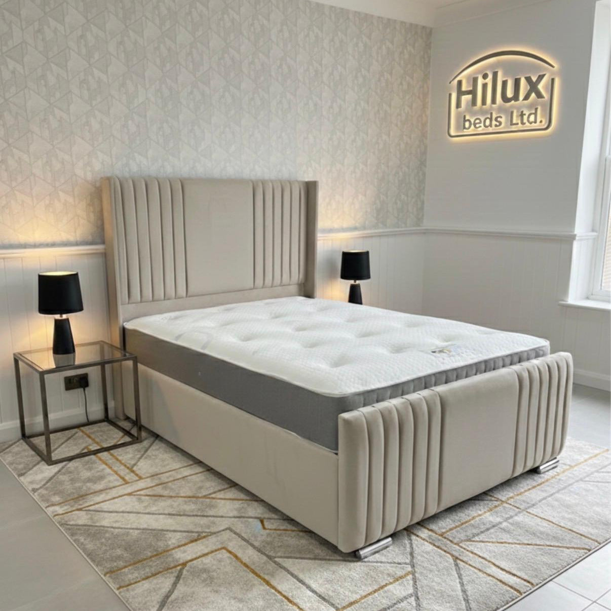 Beige upholstered bed in a modern bedroom with 'Hilux Beds Ltd' branding.