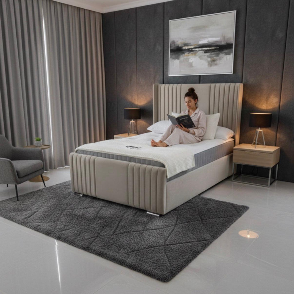 Woman reading a book on a bed in a modern bedroom with gray walls and decor.